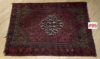 Top view of antique Persian carpet showing central medallion and geometric floral patterns, and worn edges.