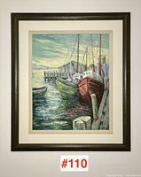 Framed painting showing the entire artwork including frame, hung on a wall, capturing the vibrant harbor scene with boats and water reflecting evening light.