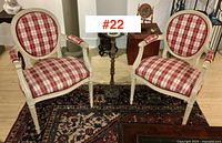 Pair of French country armchairs with oval backs and plaid upholstery shown side by side on a patterned rug.