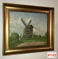 Angled photo showing the signed oil painting of a wooden windmill in a gold frame.