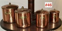 Full set of four vintage copper plated canisters with lids and brass knobs. Labels visible: Flour, Sugar, Coffee, Tea.