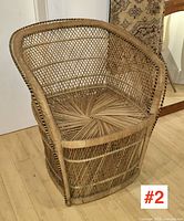 Front angled view of vintage rattan armchair showing woven lattice sides, curved armrests, and starburst woven seat pattern.