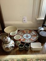 Photo showing all items in the lot including large plate, vase with lid, sake cups, small white dish, and ceramic containers