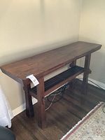 Front view of wooden sideboard showing rectangular top, sturdy legs, and open lower slatted shelf.