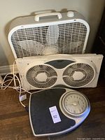 Three items including one white Lasko box fan, one white Power Zone dual-window fan with twin circular blades, and one Thinner brand analog scale with silver dial and black textured platform.