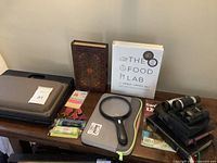 Photo of lot showing footrest, assorted books, magnifying glass, office supplies, and binoculars