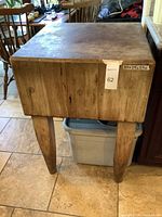View of the butcher block showing its height, wooden top surface, and tapered legs.
