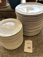 Two stacks of white plates, one larger stack of main course plates and a smaller stack of dessert plates, shown on kitchen counter.