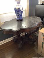 Full view of the marble wooden side table showing dark marble top with subtle white veins and scalloped edges, carved wooden apron and legs.