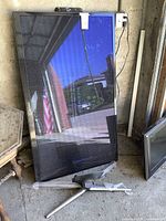 Samsung 60-inch 3D television with detached stand lying on the ground, stored in a garage environment.
