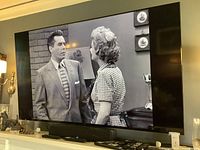 Front view of powered-on television displaying black-and-white program
