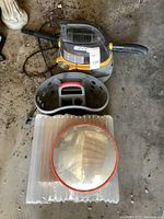 Photo showing Stinger wet/dry vacuum with black hose and caddy storage in front, convex mirror laid on corrugated plastic base.