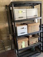 Photo of black plastic storage rack with boxes on shelves and garage background