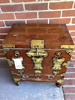 Front view of the wooden Asian chest showing brass hardware and multiple drawers.