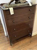 Front view of wooden four drawer chest dresser showing all drawers and signs of wear
