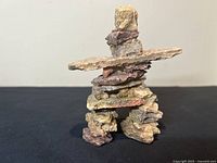 Front view of the natural stone Inuksuk sculpture showing the broad horizontal stone and stacked base stones.