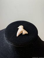 Front and side views of light beige shark tooth fossil displayed on black velvet stand, showing its pointed triangular shape and ridged root detail.