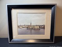 Frontal view of the framed photograph with black frame against a neutral wall.