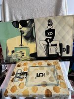 Photo showing all three Chanel perfume decorative canvases arranged together on a chair.