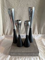 Four mid-century aluminum and iron candlesticks on a gray base, two tall and two short