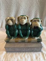 Front view of the emerald green and beige porcelain three monkey statue showing the three monkeys in hear no evil, see no evil, speak no evil poses.