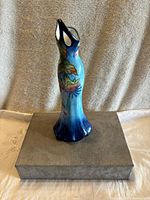 Front view of the dress-shaped vase showing hummingbird, flower designs, and blue gradient color.