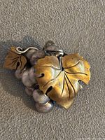 Close-up of the vintage handmade Mexican sterling silver grape cluster brooch showing detailed grape leaf with gold-tone and silver grapes cluster.