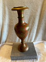 Front view of a large vintage Indian brass vase with intricate hand painted and carved floral designs.