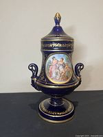 Full view of vintage Italian cobalt blue vase with lid featuring gold trim and classical hand-painted scene with two women and cherub