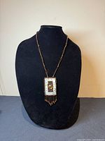 Full view of vintage Native American First Nation beaded necklace with leather-back rectangular pendant, featuring mother of pearl and smoky quartz details, displayed on black jewelry bust.