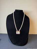 Front view of the vintage Native American beaded necklace with moccasin pendant on a black display bust.