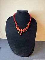 Front view of vintage natural coral nugget necklace displayed on black bust showing natural coral texture and bead arrangement