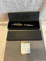 Black vintage Pierre Belvedere ballpoint pen with silver ornate bands, displayed inside original black box with lid and certificate below.