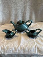 Photo of tea set from front angle showing teapot with lid and two matching creamers