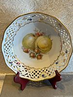 Front view of the vintage pierced Schumann Bavaria bowl showing painted yellow fruit and nuts, intricate pierced lattice work sides with gold trim and painted floral accents.