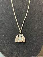 Front view of the silver-tone metal raven pendant with turquoise, coral-red, and white enamel on cord necklace.