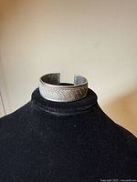 Front left angle view of the sterling silver cuff bracelet showing the woven pattern on the band