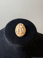Front view of the oval carved bone cameo brooch showing detailed relief of Three Graces.