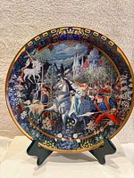 Front view of the round collector’s plate showing unicorn hunting medieval scene with knights, horses, castle, and floral border.