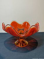 Front angled view of Viking Glass amberina compote, showing the wavy handkerchief petal rim, pedestal base, and vivid orange-red color.