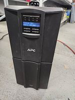 Front view of APC Smart-UPS 2200VA showing LCD display panel with operational status.