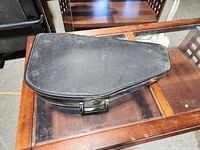 Closed black hard case for the autoharp with a leather or faux leather exterior, zippered edges, and handle on top.