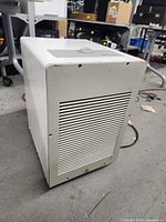Side angle view of white automatic dehumidifier showing vented panel and overall shape.
