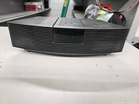 Front view of black Bose Wave Radio with speaker grille and central control panel under display window.