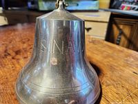 Close-up of brass bell showing 'US NAVY' inscription on side.