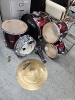 Full view of Excel drum set parts including bass drum with pedal, two tom-toms, snare drum, and cymbal.