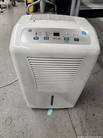 Front view of the white GE dehumidifier showing air intake grille and control panel with buttons and indicator lights.