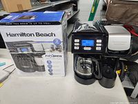 Hamilton Beach FlexBrew coffee maker with box and unit on table, showing overall condition and packaging.