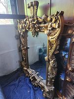 Full front view of large gilded mirror leaning against wall