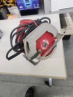 Top angled view of Milwaukee circular saw showing red blade guard, power cord coiled on top, and overall condition.